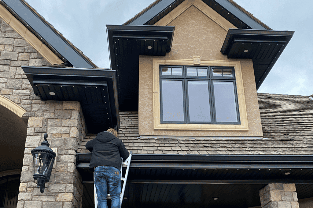 man installing permanent trim lights on a house